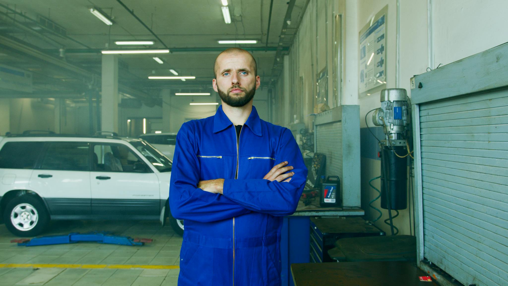 A Man in Blue Boilersuit Standing near a White Car