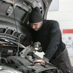 Man in Black Jacket and Black Knit Cap Inspecting Car Engine